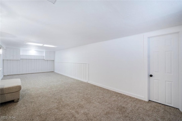 below grade area featuring a wainscoted wall and carpet flooring