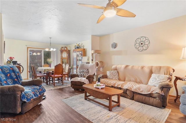 living area featuring ceiling fan with notable chandelier, a textured ceiling, and wood finished floors