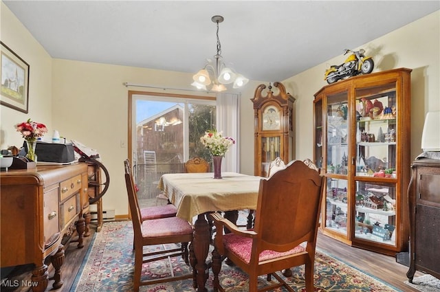 dining area featuring a baseboard radiator, an inviting chandelier, and wood finished floors