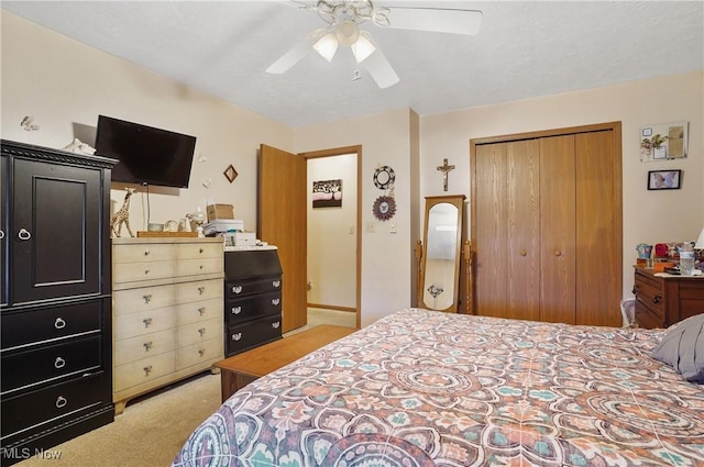 bedroom with a ceiling fan, a closet, and light colored carpet