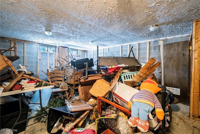 miscellaneous room with concrete block wall, a garage, concrete floors, and visible vents