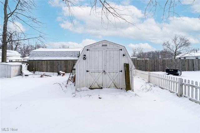 snow covered structure featuring fence and a shed