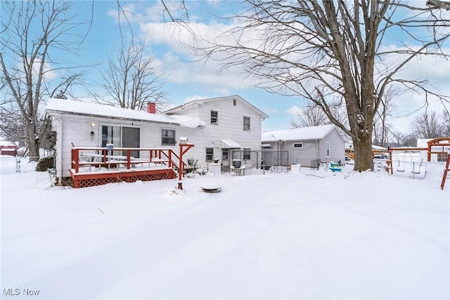 snow covered back of property with a chimney and a deck