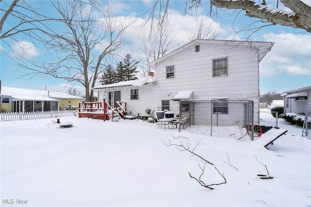 snow covered back of property with fence and a wooden deck