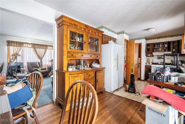 kitchen with white fridge with ice dispenser, wood finished floors, and glass insert cabinets