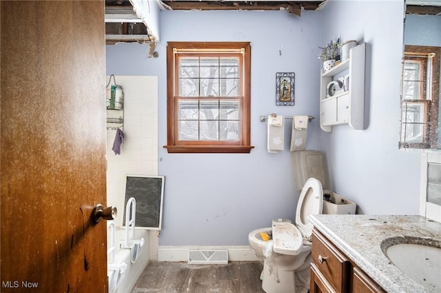 full bathroom with visible vents, toilet, vanity, a tub, and baseboards