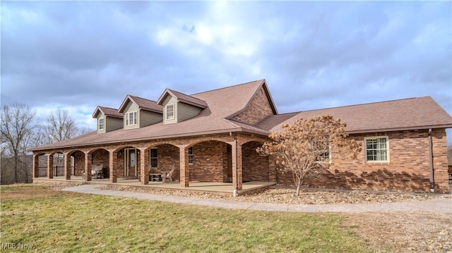 exterior space featuring covered porch, brick siding, and a front lawn