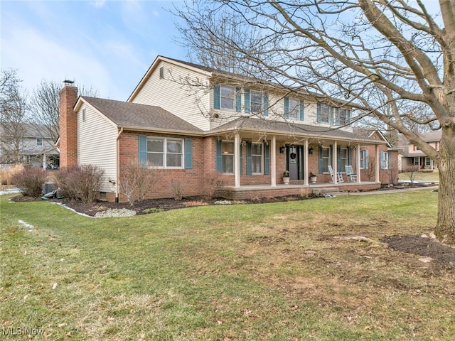 view of front facade featuring covered porch, brick siding, a chimney, and a front lawn