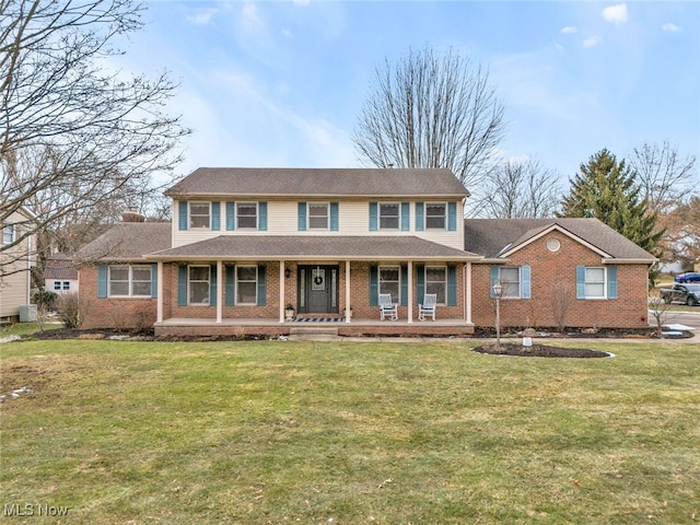 view of front facade with a porch, a chimney, and a front lawn