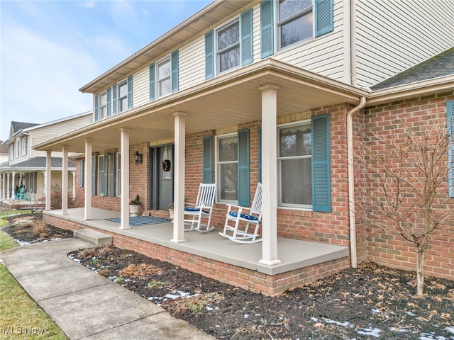 view of exterior entry with covered porch and brick siding