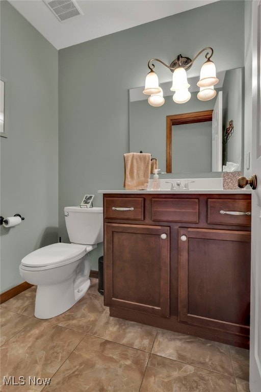 half bath with baseboards, visible vents, toilet, vanity, and a chandelier