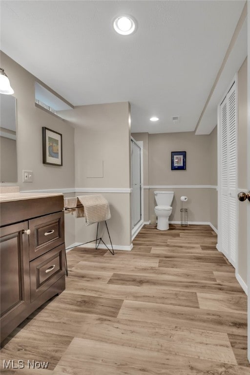 bathroom featuring toilet, wood finished floors, a closet, and vanity