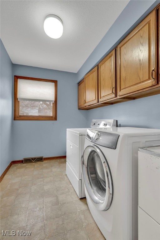 laundry room with cabinet space, baseboards, visible vents, and washing machine and clothes dryer