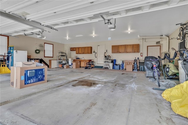 garage featuring freestanding refrigerator and a garage door opener