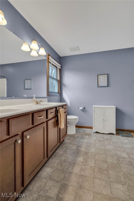 bathroom featuring toilet, baseboards, and vanity