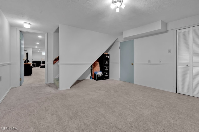 additional living space featuring a textured ceiling and light colored carpet