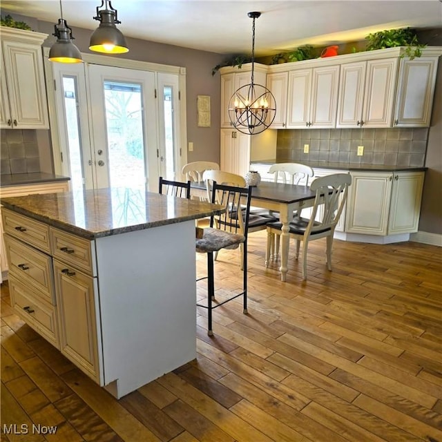 kitchen featuring a kitchen island, cream cabinetry, hanging light fixtures, and hardwood / wood-style floors