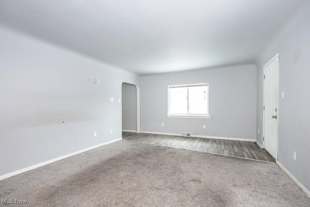 unfurnished room with arched walkways, carpet, visible vents, and baseboards