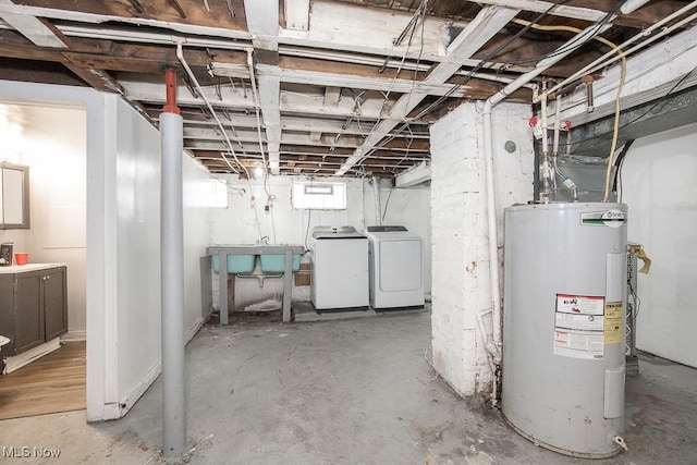 below grade area with separate washer and dryer, a sink, and electric water heater