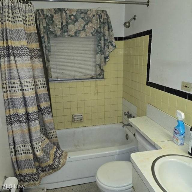 full bath with shower / tub combo, toilet, speckled floor, vanity, and tile walls