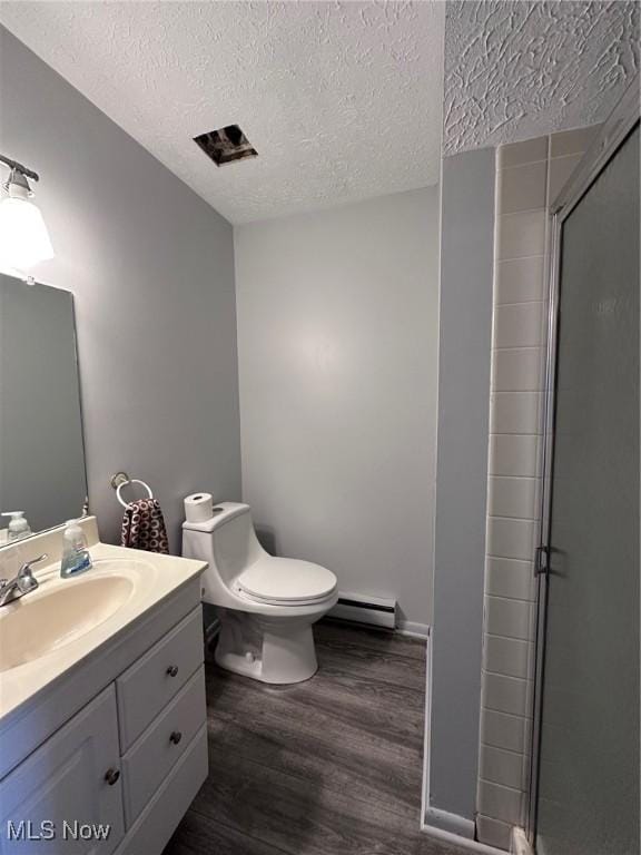 full bath with wood finished floors, a baseboard heating unit, a textured ceiling, a shower stall, and vanity