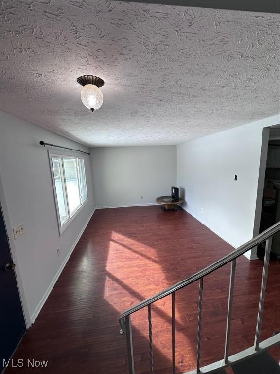 unfurnished room with dark wood-style floors, baseboards, and a textured ceiling