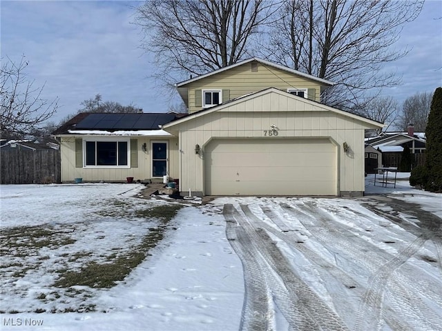 view of front facade featuring a garage, fence, and solar panels