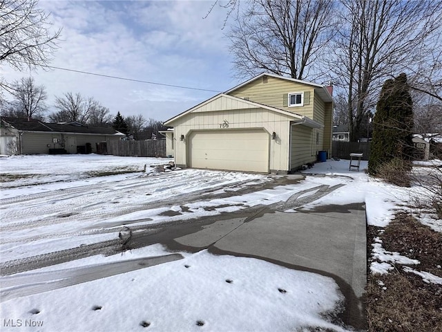 view of snowy exterior with a garage and driveway