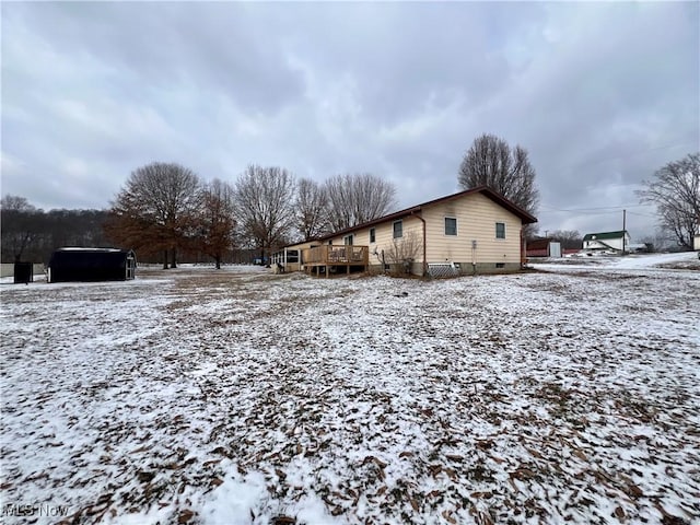 view of snow covered exterior with crawl space and a wooden deck