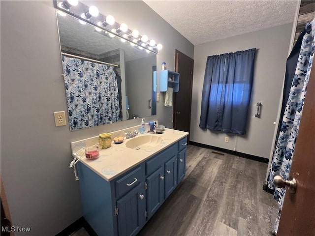 bathroom featuring a textured ceiling, curtained shower, wood finished floors, vanity, and baseboards