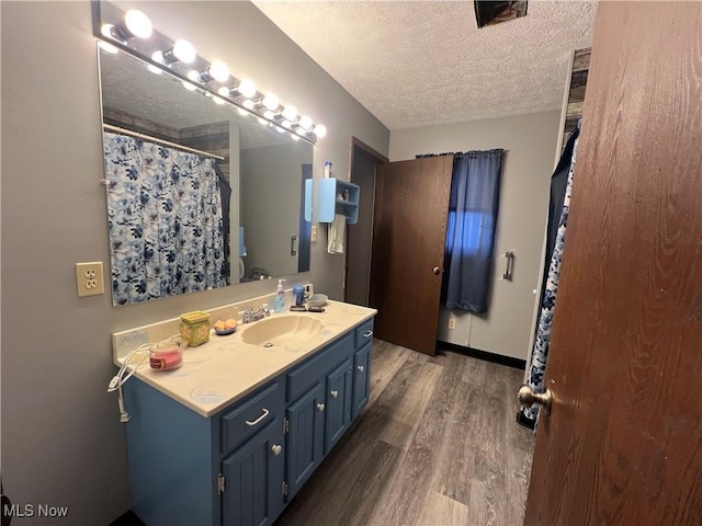 full bath featuring baseboards, a textured ceiling, vanity, and wood finished floors