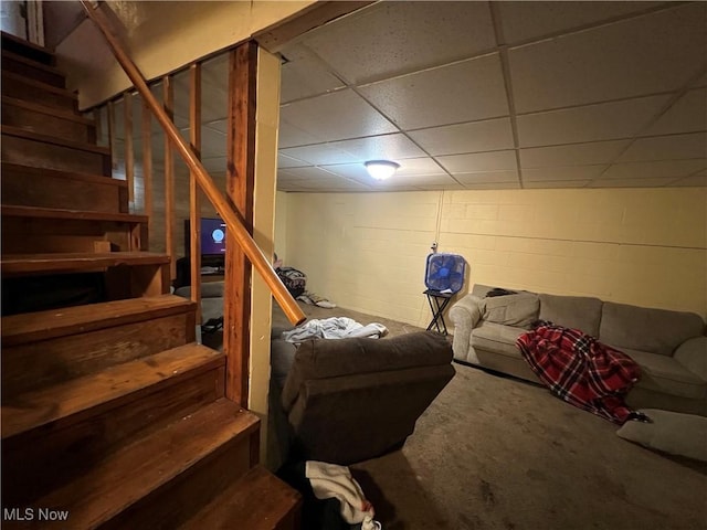 interior space featuring concrete block wall, a drop ceiling, and stairway