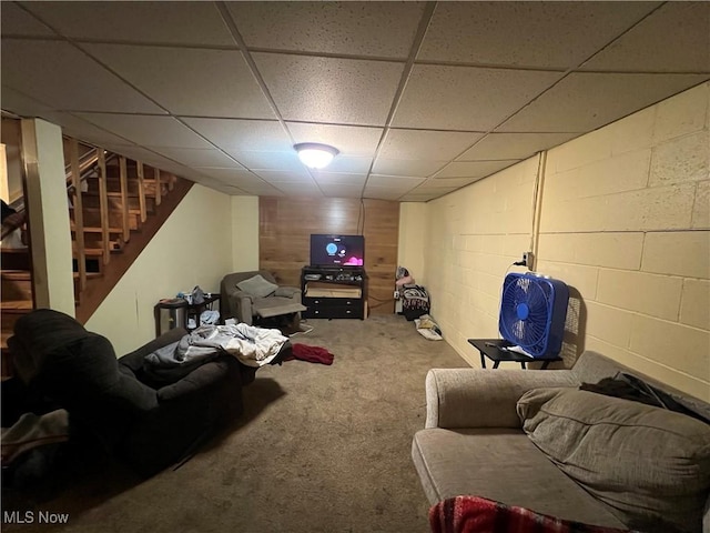 living area featuring carpet floors, stairway, and concrete block wall