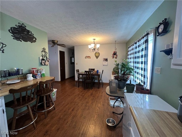 dining area featuring a textured ceiling, dark wood-style flooring, and ceiling fan with notable chandelier