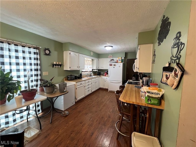 kitchen with dark wood finished floors, white cabinets, freestanding refrigerator, light countertops, and a sink