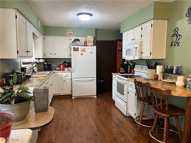 kitchen featuring white appliances, white cabinets, dark wood-style floors, light countertops, and a sink