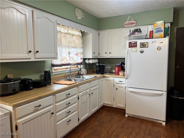 kitchen featuring freestanding refrigerator, light countertops, a sink, and white cabinetry