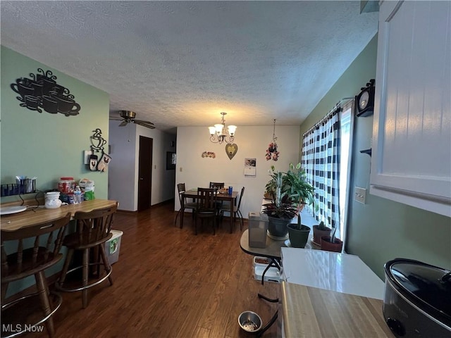 dining space featuring a textured ceiling, dark wood-style flooring, and ceiling fan with notable chandelier