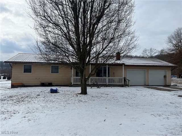 view of front of house featuring a garage, a chimney, and metal roof