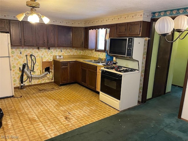 kitchen featuring black microwave, light countertops, freestanding refrigerator, light floors, and range with gas cooktop