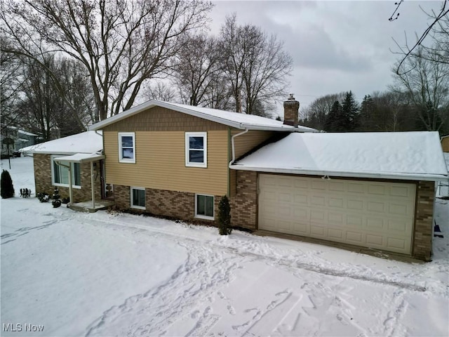 view of front of property featuring a garage, brick siding, and a chimney