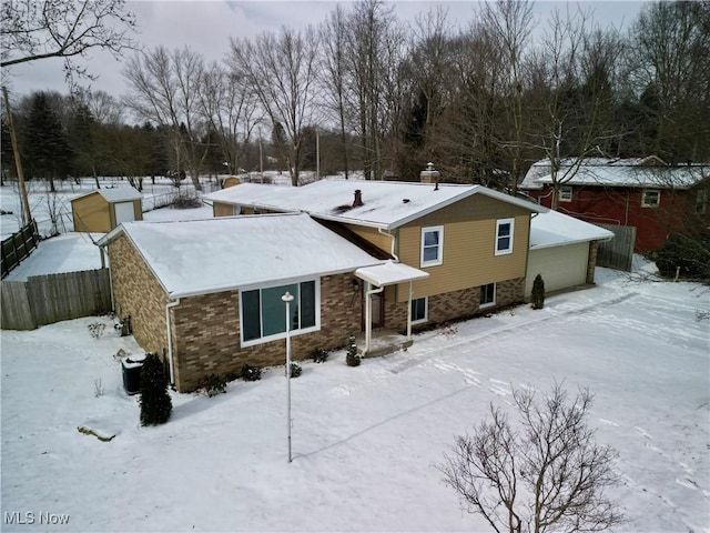 view of front of property with a garage, brick siding, and fence