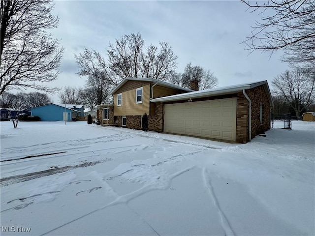 view of snow covered exterior with a garage and brick siding