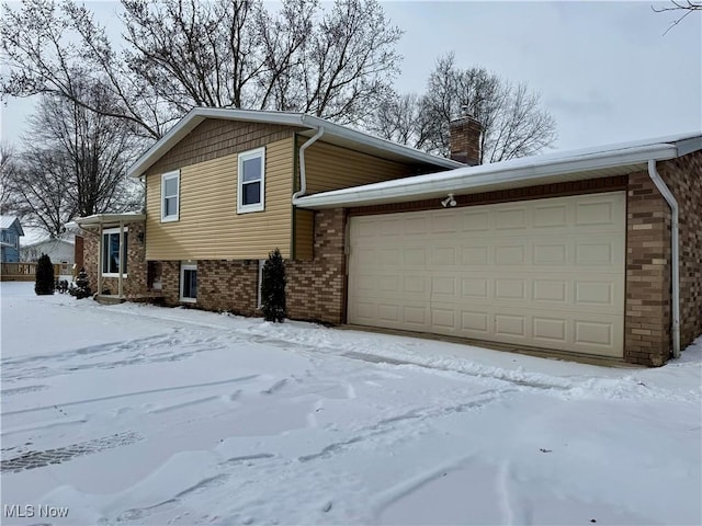 view of front of home with a garage, brick siding, and a chimney