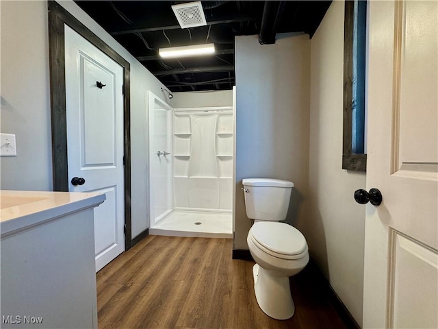 bathroom featuring visible vents, toilet, a stall shower, vanity, and wood finished floors