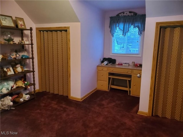 interior space with vaulted ceiling, baseboards, and dark colored carpet