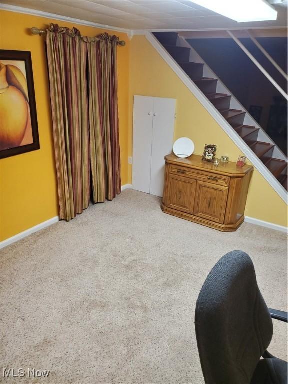 living area with ornamental molding, light carpet, stairway, and baseboards