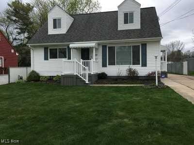 new england style home with driveway, fence, and a front yard