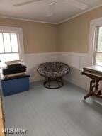 unfurnished room featuring a wainscoted wall, crown molding, and ceiling fan