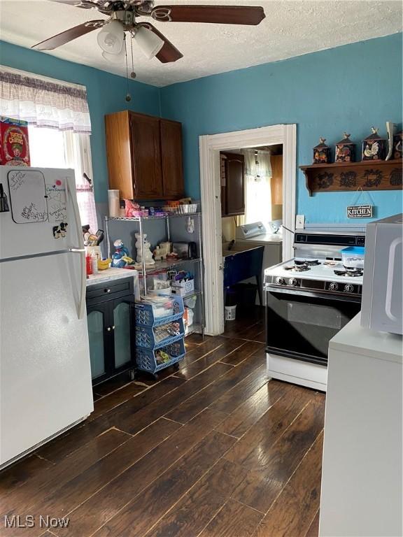 kitchen with plenty of natural light, white appliances, light countertops, and dark wood finished floors